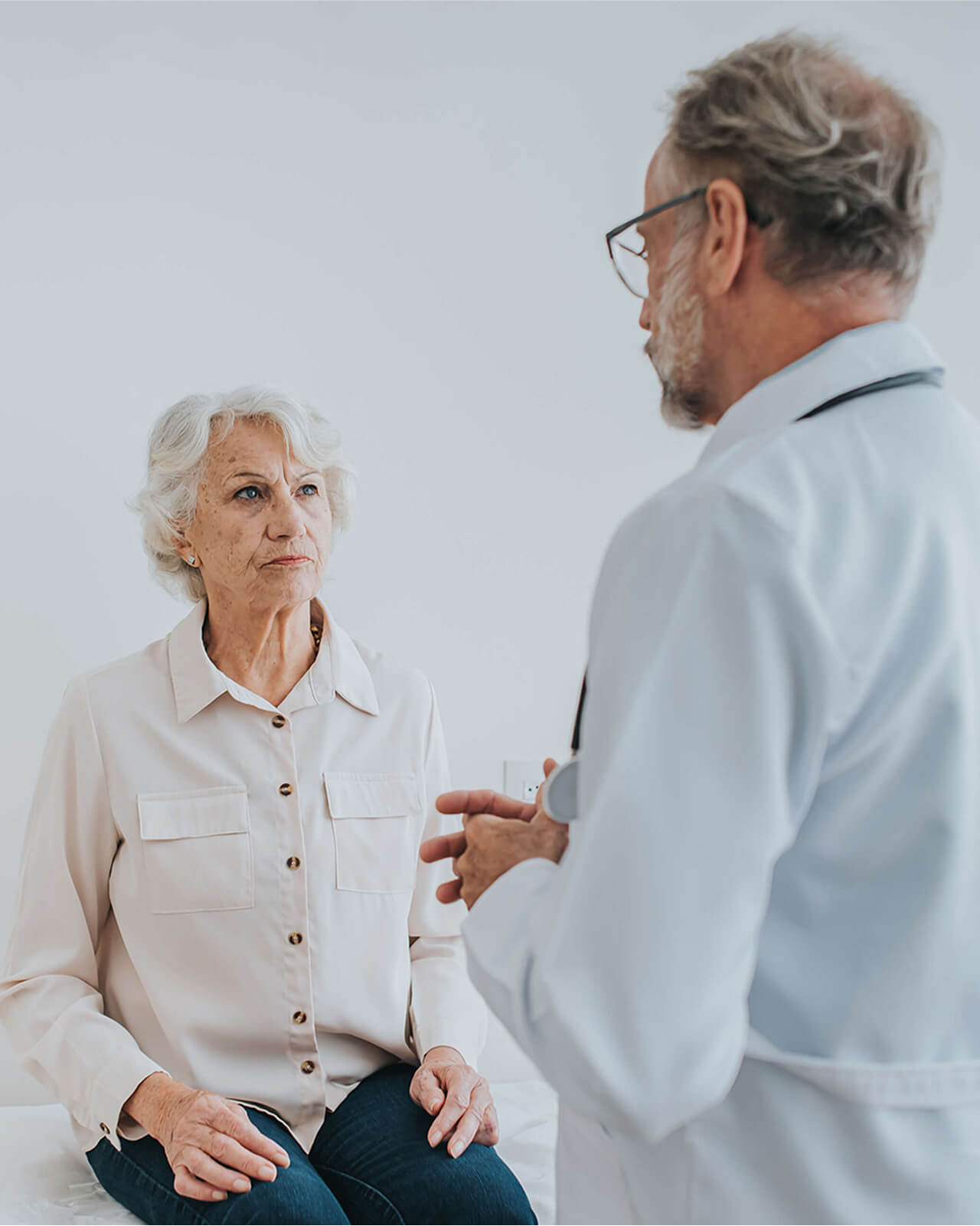 A doctor speaking with a patient who is sitting on an exam table.